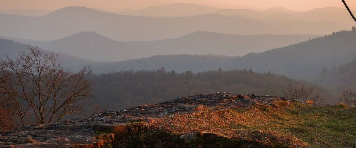 A mountainous landscape with a rocky outcrop and a metal railing.