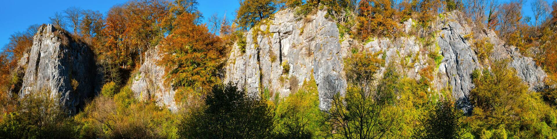 The “Sieben Jungfrauen” (Seven virgins) are a well-known limestone rock formation in the idyllic Hönne Valley in the Sauerland (Germany). Wide-angle panorama on sunny a autumn ay with colorful leaves