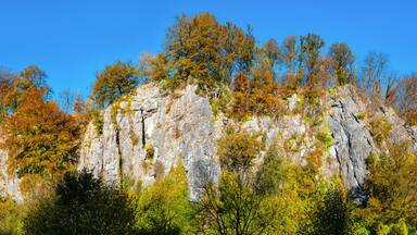 The “Sieben Jungfrauen” (Seven virgins) are a well-known limestone rock formation in the idyllic Hönne Valley in the Sauerland (Germany). Wide-angle panorama on sunny a autumn ay with colorful leaves