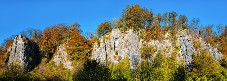 The “Sieben Jungfrauen” (Seven virgins) are a well-known limestone rock formation in the idyllic Hönne Valley in the Sauerland (Germany). Wide-angle panorama on sunny a autumn ay with colorful leaves
