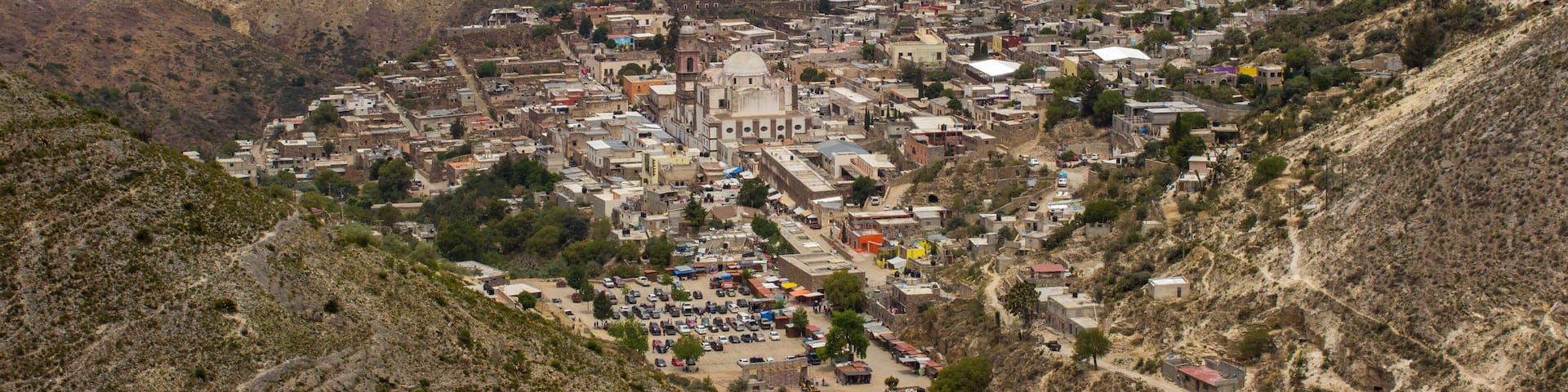 A mountainous town with a prominent church, winding roads, and sparse vegetation.