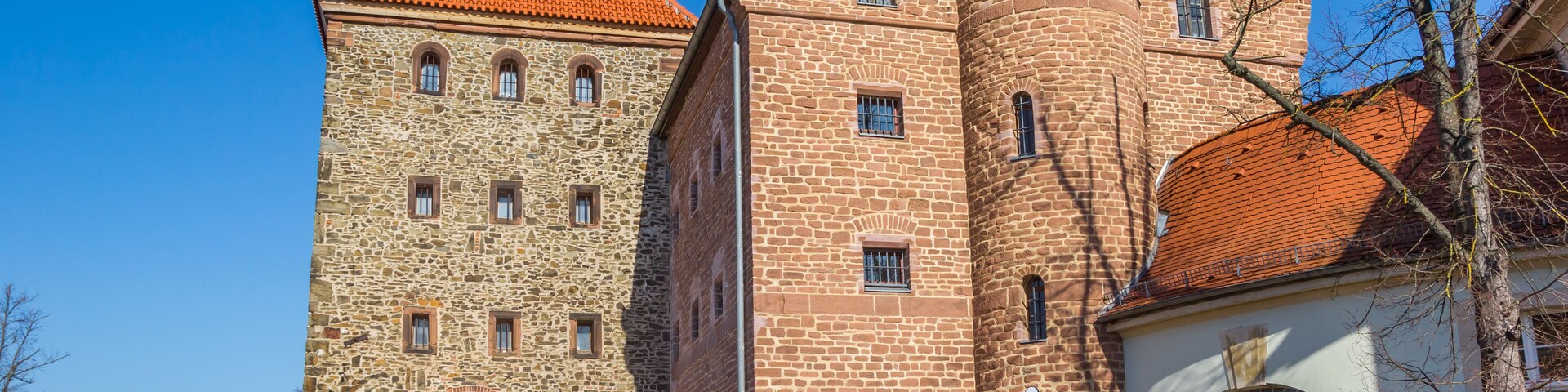 Un edificio histórico de piedra con tejado de tejas rojas y una torre.