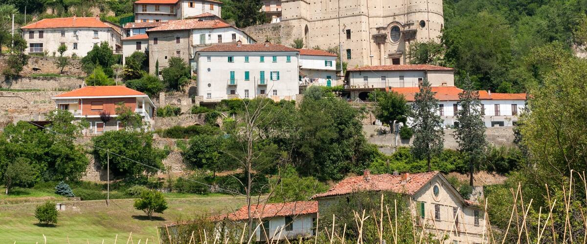 A historic town with a prominent church on a hillside, surrounded by traditional buildings and lush greenery.