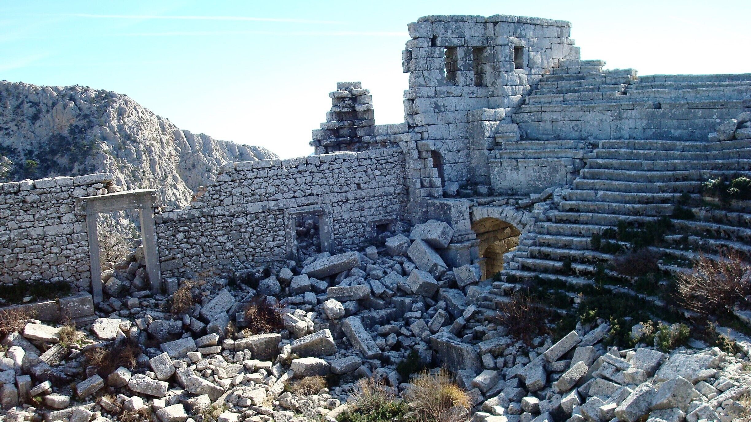 Ruinas antiguas de piedra con un muro parcialmente conservado y escalones.