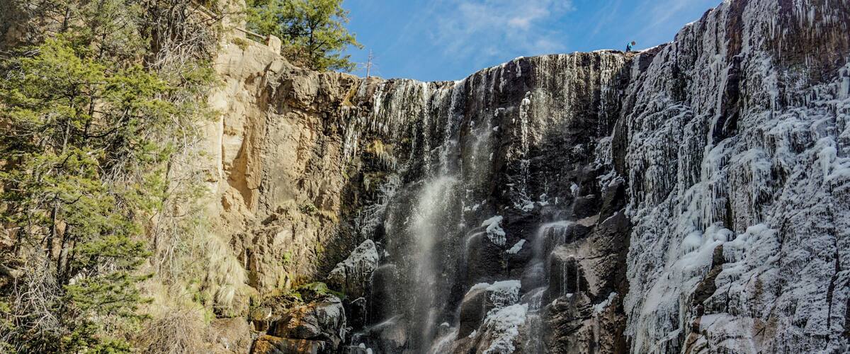 A waterfall cascading down a rocky cliff surrounded by trees.