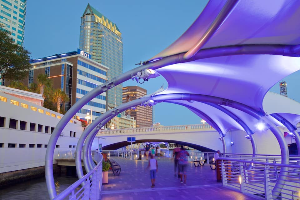 Un puente peatonal de diseño moderno, con vistas a un río y una embarcación amarrada a la izquierda.