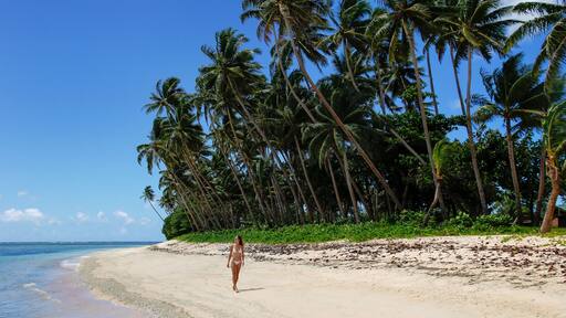 Young woman in bikini walking on a beach in Lavena village on Taveuni Island, Fiji