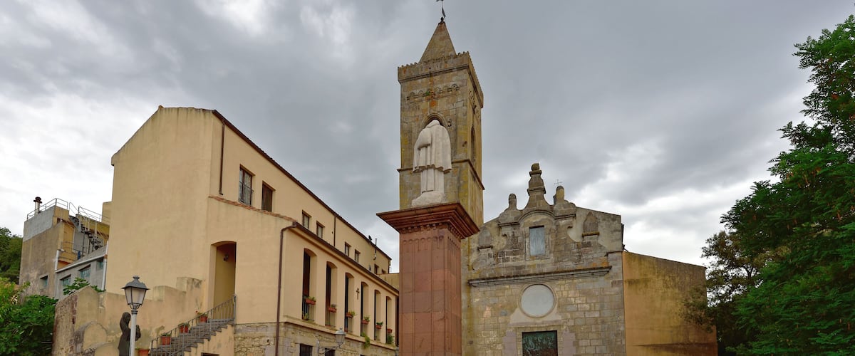A historic square with a church, a fountain, and potted plants.