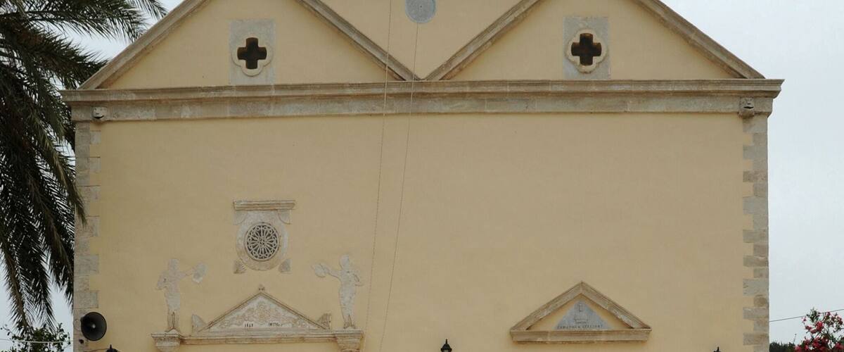 A church with a bell tower, two doors, and a cross on the facade.