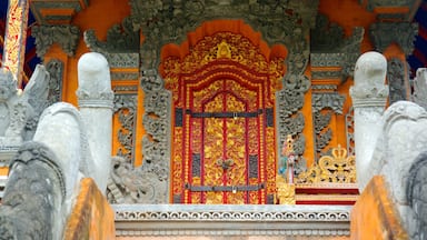 Entrada de um templo ornamentado, com esculturas detalhadas e uma porta vibrante em vermelho e dourado.
