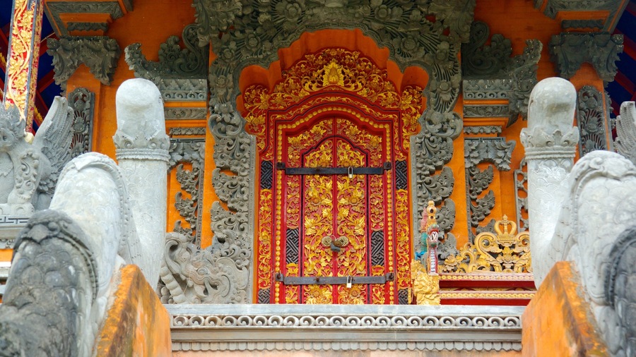 Una entrada de templo ornamentada con intrincados grabados y una puerta roja y dorada vibrante.