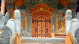 An ornate temple entrance with intricate carvings and a vibrant red and gold door.