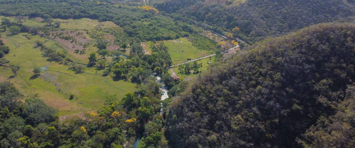 A valley with a river, green fields, and forested hills.