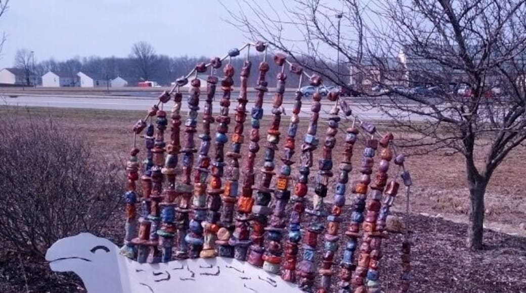 A dinosaur sculpture with a metal body and a fin made from painted chunks of clay.