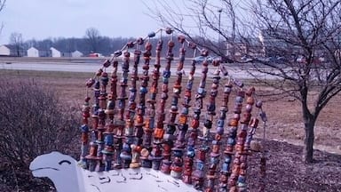 A dinosaur sculpture with a metal body and a fin made from painted chunks of clay.