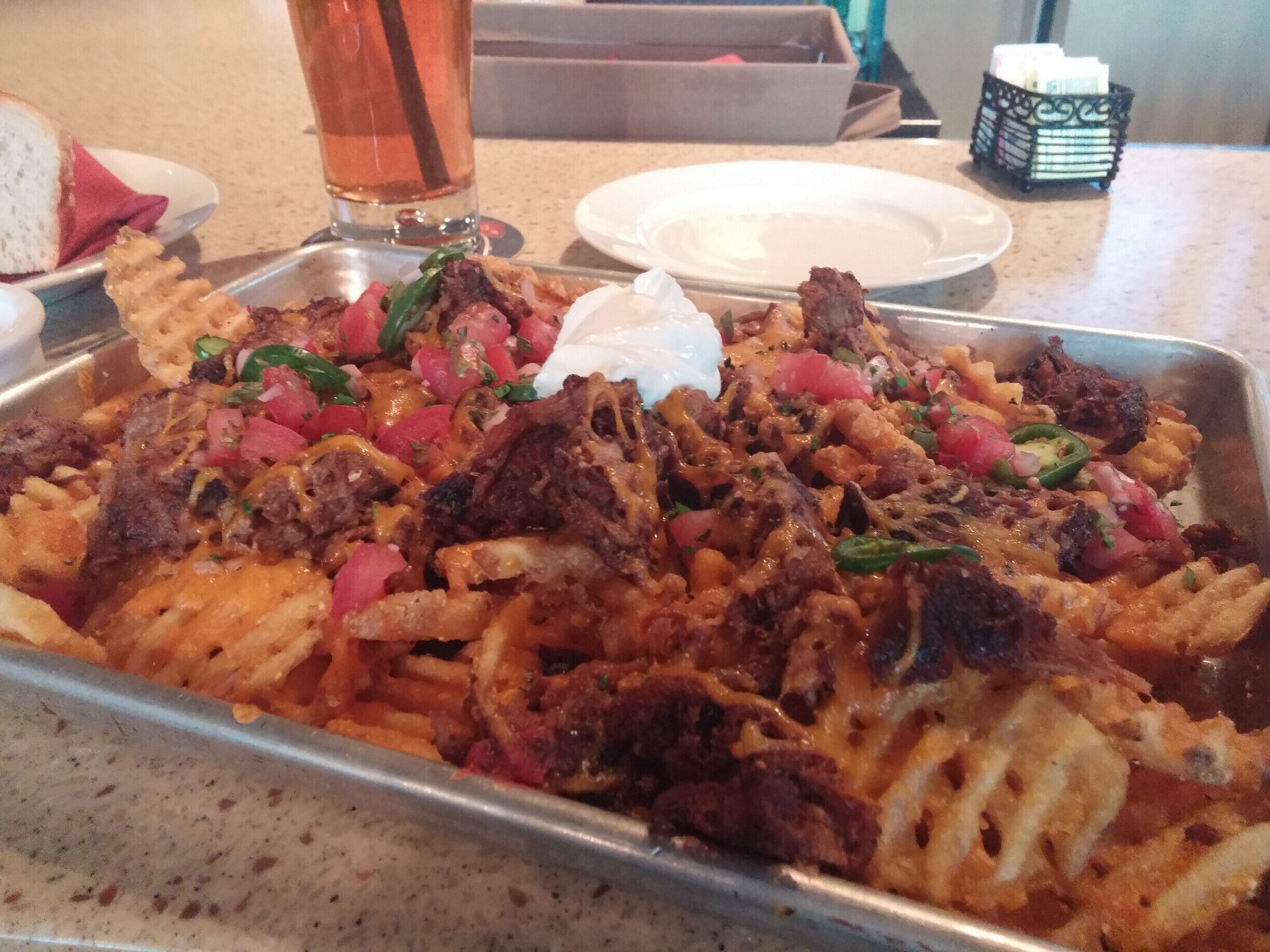 Waffle nachos!

Masa-crusted waffle fries topped with smoked pulled pork, cheddar cheese, salsa, jalapenos, cilantro and sour cream.