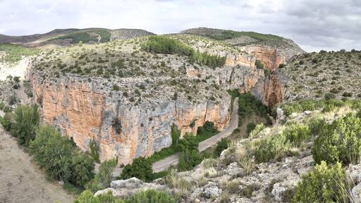 The Barranco de la Hoz Seca (Dry Defile Gully) canyon, with scarps, bushes and red rocks, in a cloudy atumn, in the Jaraba rural town, Aragon, Spain