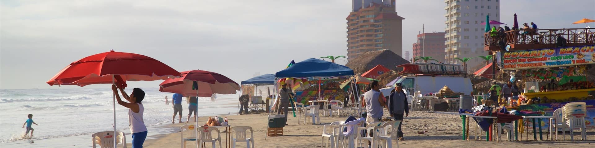 A beach with umbrellas, chairs, and people.