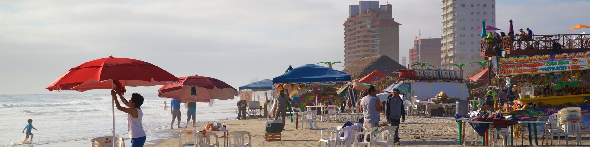 Una playa con sombrillas, sillas y gente.