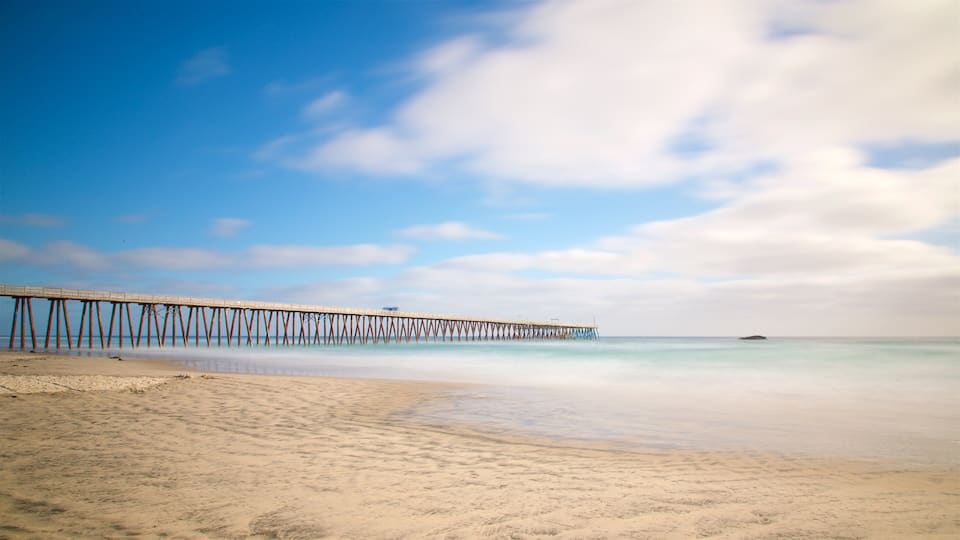 A beach with a long pier extending into the ocean.