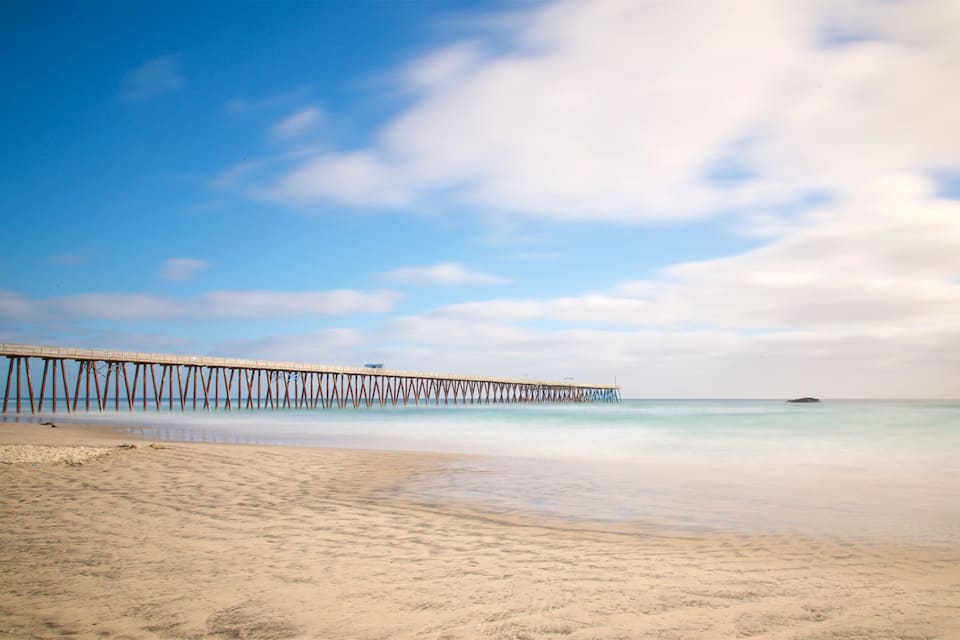 A beach with a long pier extending into the ocean.