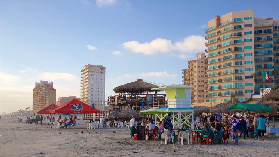 A beach with people, a lifeguard tower, and tall buildings in the background.