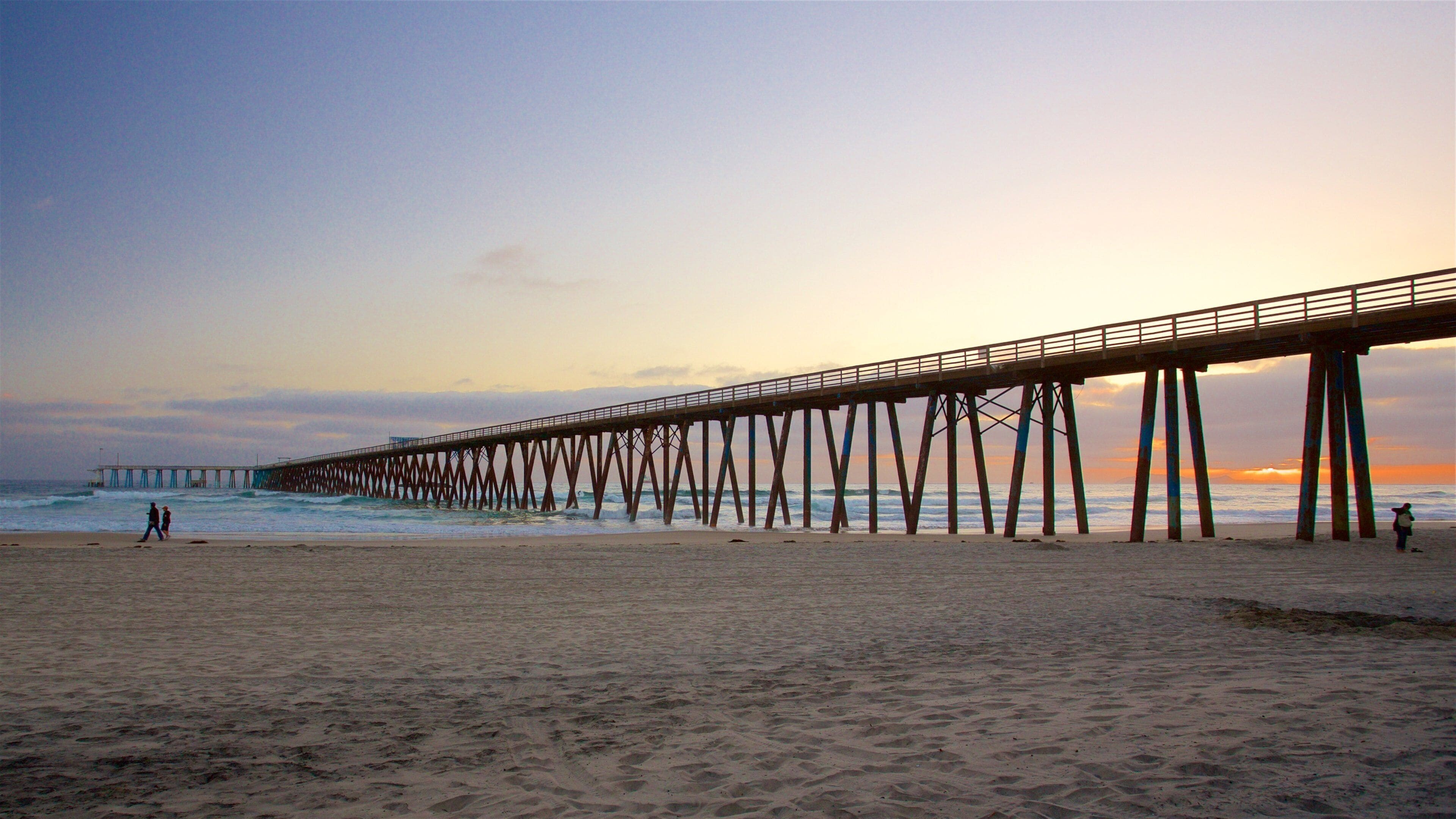 Un muelle que se adentra en el océano al atardecer.