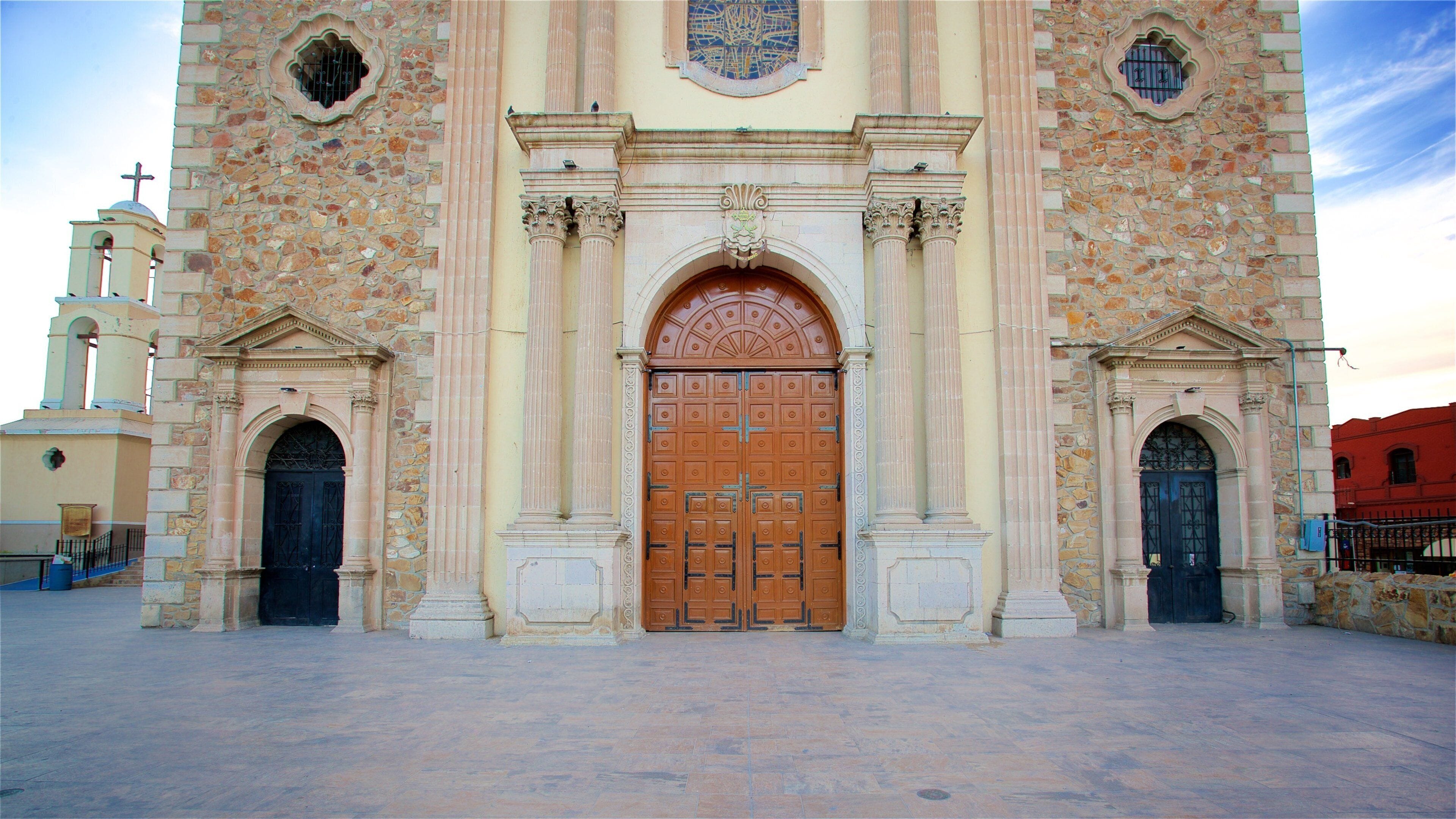 Una iglesia de piedra grande con un arco central, flanqueado por dos arcos más pequeños y una torre del campanario.