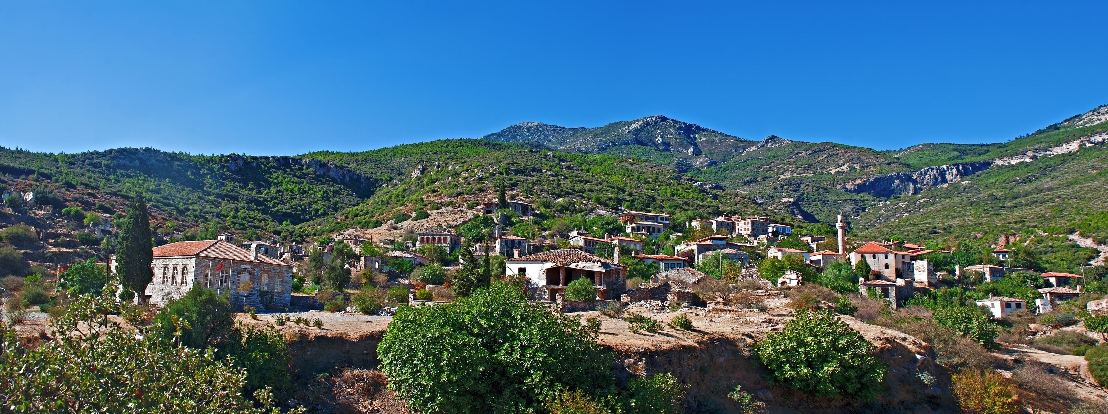 A village nestled in a valley with mountains in the background.