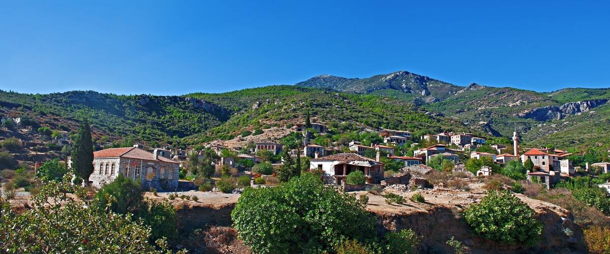 A village nestled in a valley with mountains in the background.