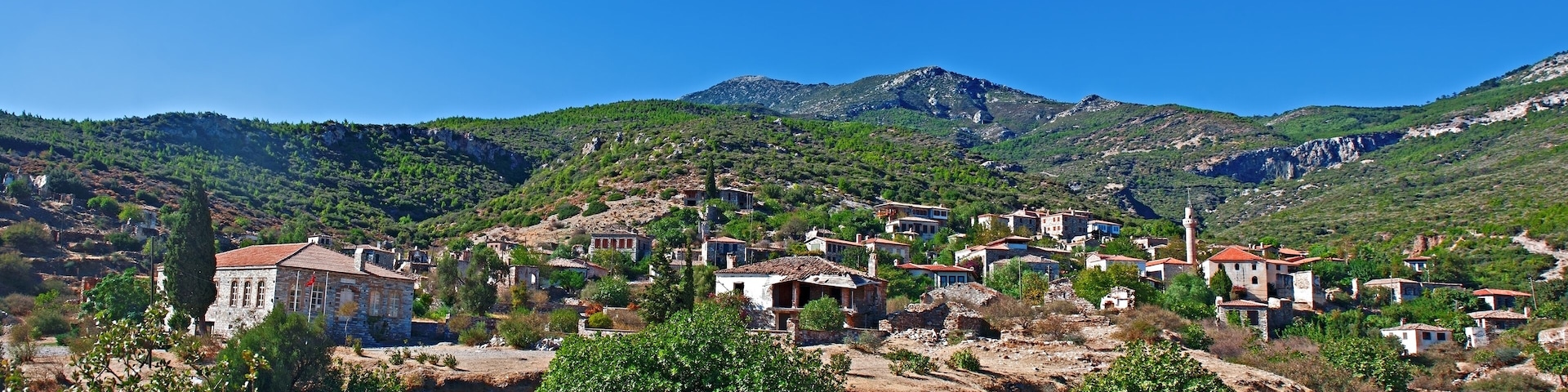 A village nestled in a valley with mountains in the background.