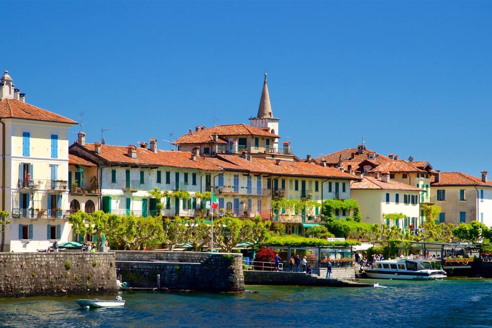 A waterfront town with historic buildings, a church spire, and boats on the water.