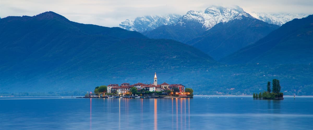 A lakeside town with a prominent church and mountains in the background.