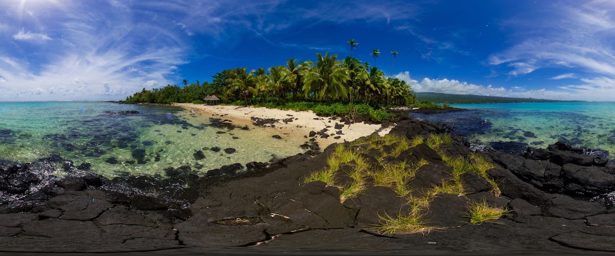 A tropical island with clear turquoise waters, a sandy beach, and lush greenery.