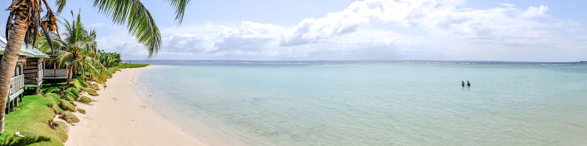 Panorama over Manase Beach, Savai'i Island, Samoa, South Pacific - with people in water and traditional beach fale accommodation