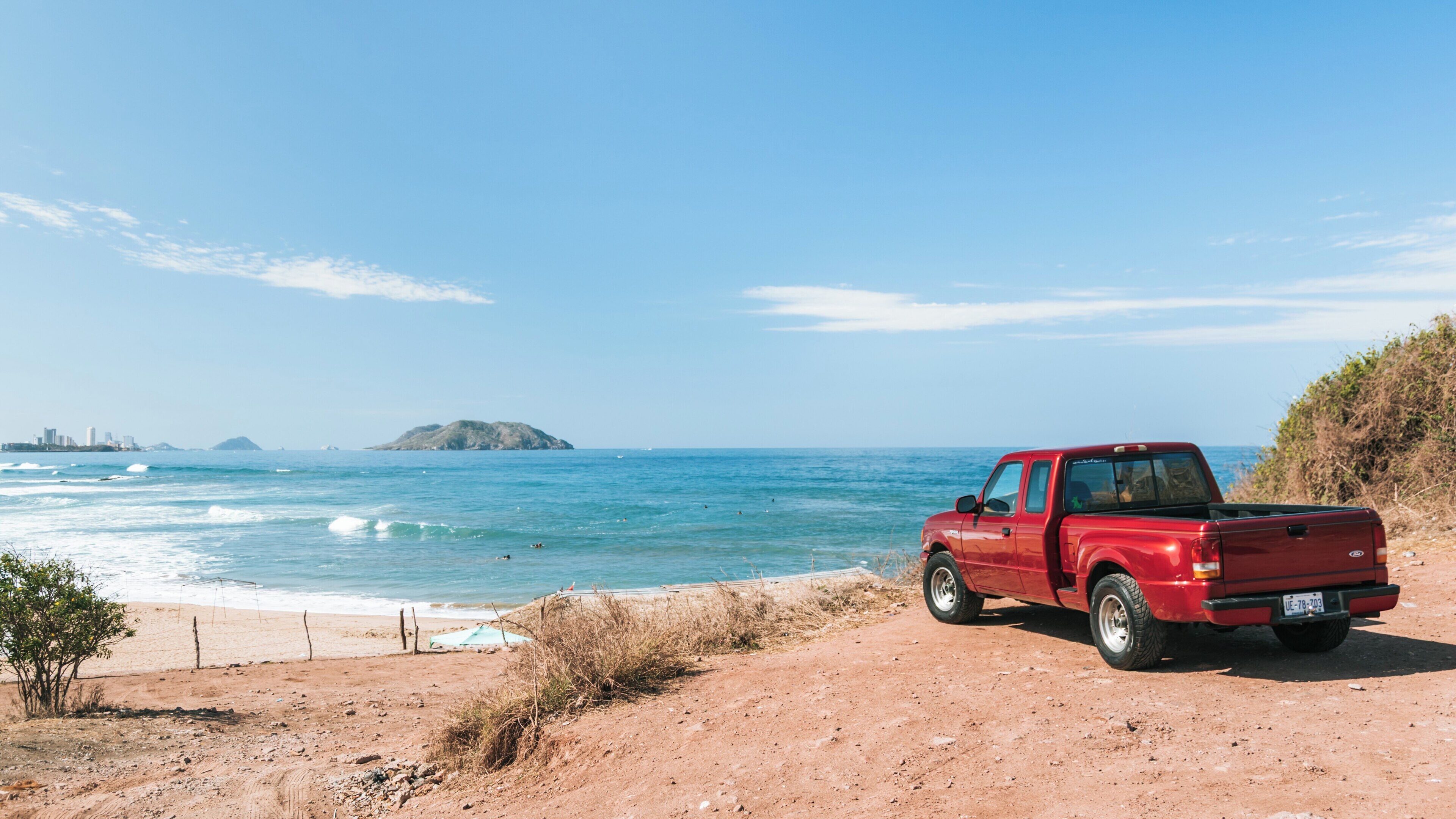 Relaxing at Witches Beach in Cerritos, Mazatlán with ocean views and a red pickup truck under a clear blue sky on a sunny day