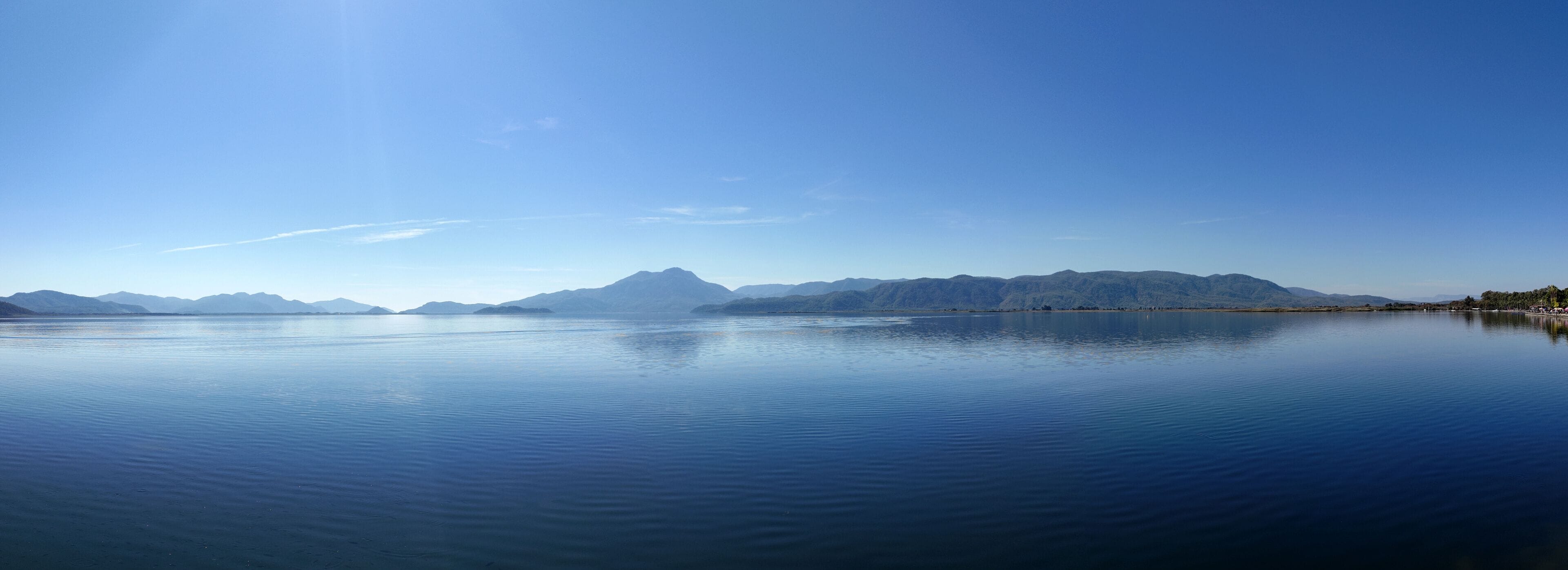 Tranquil Lake Koycegiz panorama under a bright summer sky, with calm waters reflecting the sunlight, Mugla, Turkey.