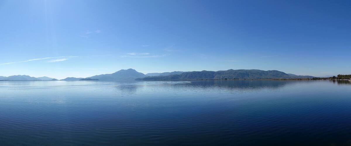 A calm lake with mountains in the background.
