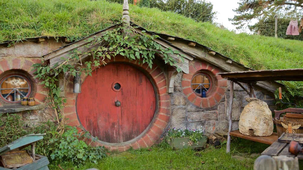 A Hobbit-style house with a red door, two round windows, and a thatched roof.