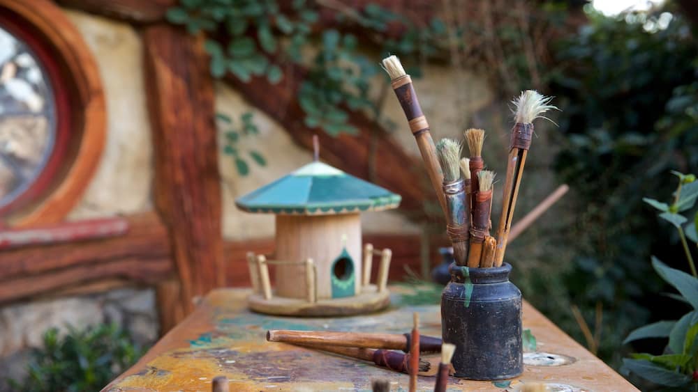Une table rustique avec des pinceaux et une nichoir.