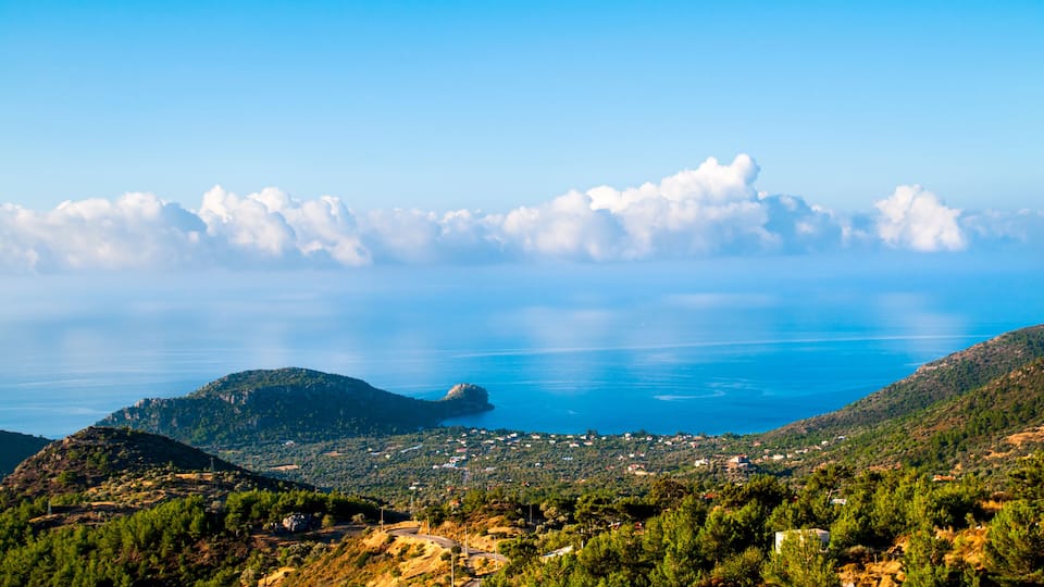 A coastal landscape with a town, hills, and a body of water.