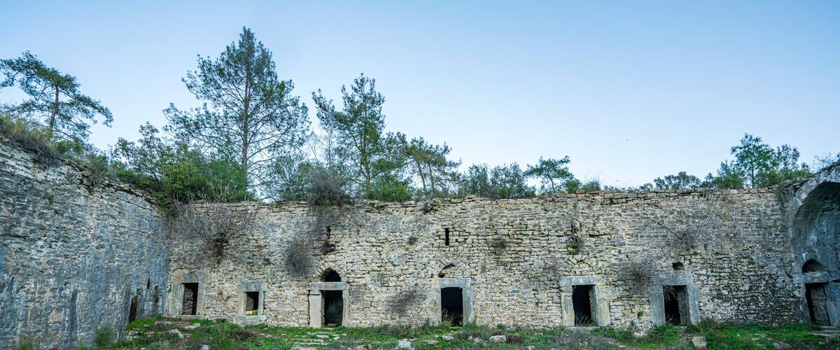 An ancient stone building with arched doorways and a grassy courtyard.