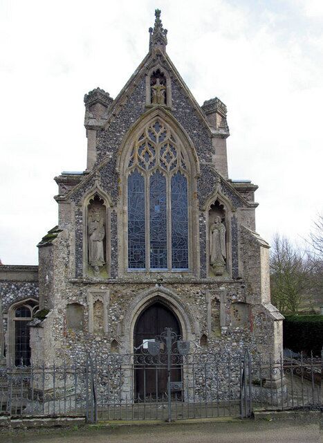 A Gothic-style church with a tall steeple, pointed arch windows, and a large stained glass window.
