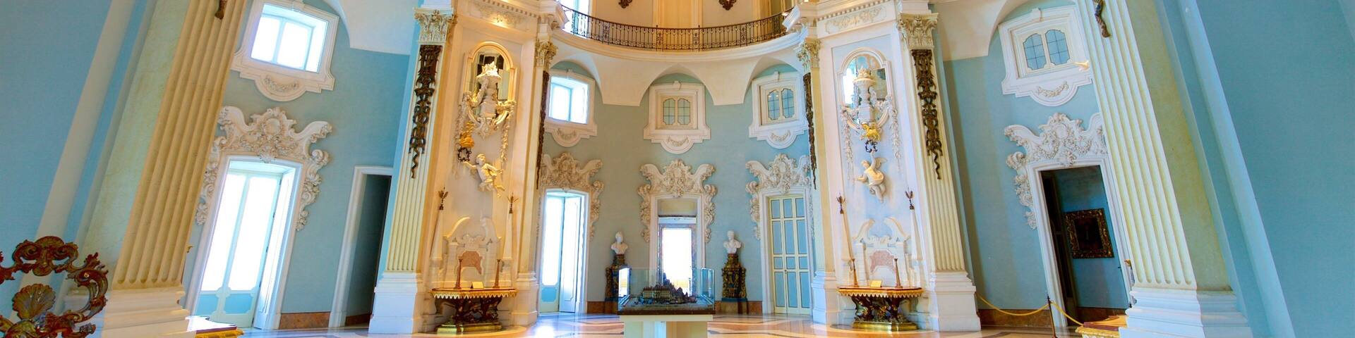 A grand hall with ornate ceilings, large windows, and classical columns.