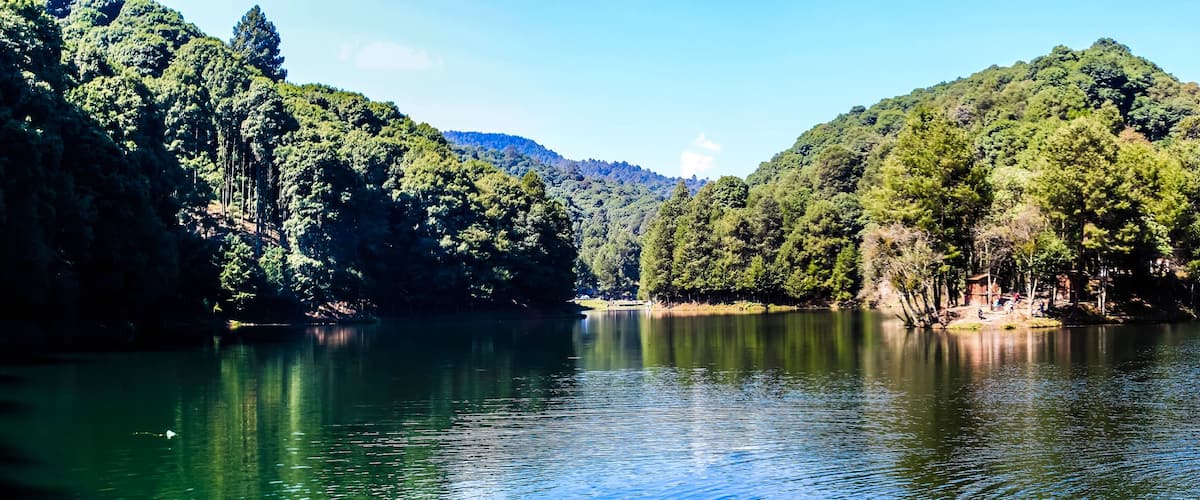 A calm lake surrounded by dense forests and hills.
