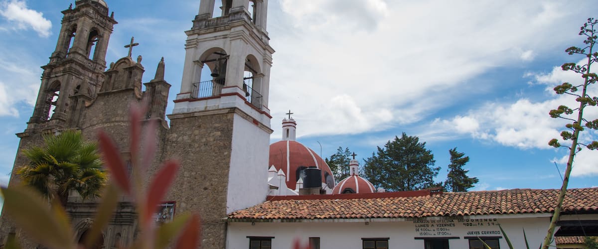 A historic church with bell towers and domes, surrounded by greenery.