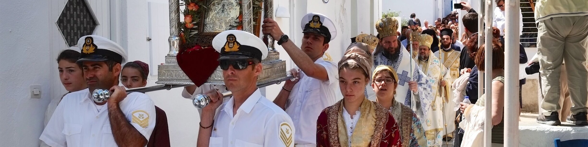 Apollonia Απολλωνία, Sifnos. The biggest festival of all is that of the patron saint of the island, Panagia Chrysopigi, celebrated on Ascension Day, attended by many people from all over the island and beyond. In the afternoon of the day before, the miracle icon of Zoodochou Pigis (the Life-Giving Spring) is ‘transported’ from the home of the ‘panigiras’ and the festival procession, with the clergy and the faithful, follows the path to the Holy Church of Agios Georgios in Kamares where the liturgy is held. Then the clergy, with the ‘panigiras’ carrying the icon, board the ferry that each year on this day adds the sacred rock of Chrysopigi to its route from Piraeus. The ship does not carry the believers because disembarkation is potentially dangerous. The crowd of believers, local people and visitors, take the road to Chrissopigi where the arrival of the icon is greeted with great enthusiasm, and the celebrations are honoured by music of the Coast Guard band.