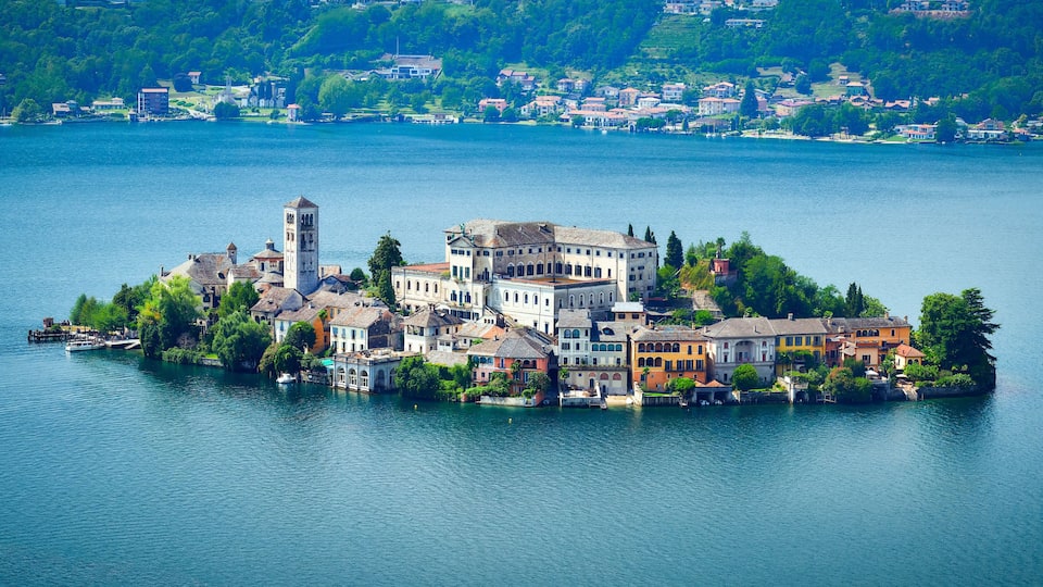 A lakeside town with historic buildings, a prominent tower, and lush greenery.