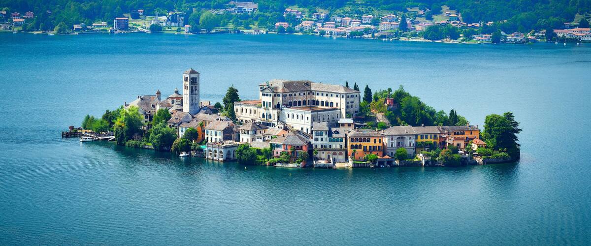 A lakeside town with historic buildings, a prominent tower, and lush greenery.