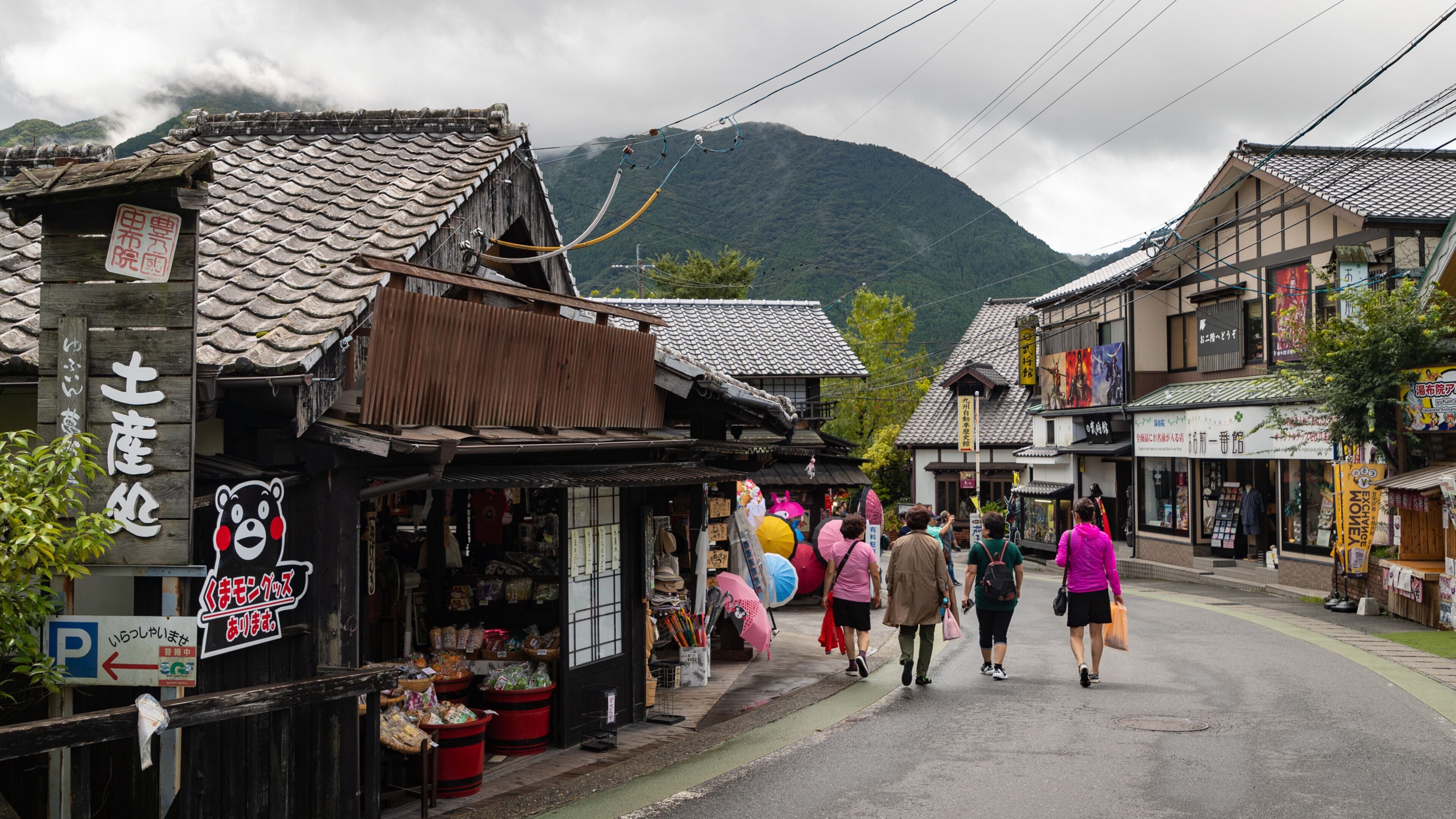 A traditional Japanese street with wooden buildings, a bear sign, and people walking.